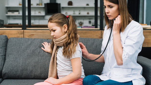 Primer plano de una doctora comprobando a la niña enferma con estetoscopio