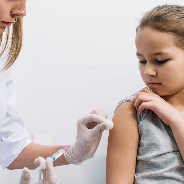 Foto gratuita primer plano de la doctora dando una inyección en el brazo del paciente