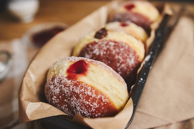 Primer plano de donuts esponjosos con mermelada en un recipiente bajo las luces