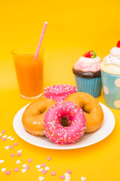 Primer plano de donuts, magdalenas y vaso de jugo