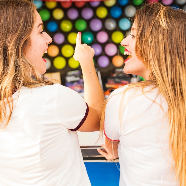 Primer plano de dos amigas disfrutando de un juego en el parque de diversiones