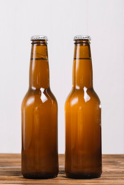 Primer plano de dos botellas de cerveza en la superficie de madera