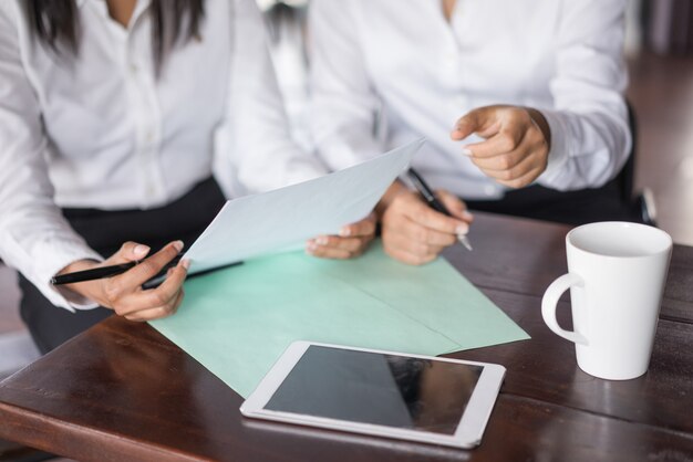 Primer plano de dos colegas mujeres que trabajan con documentos en la mesa.