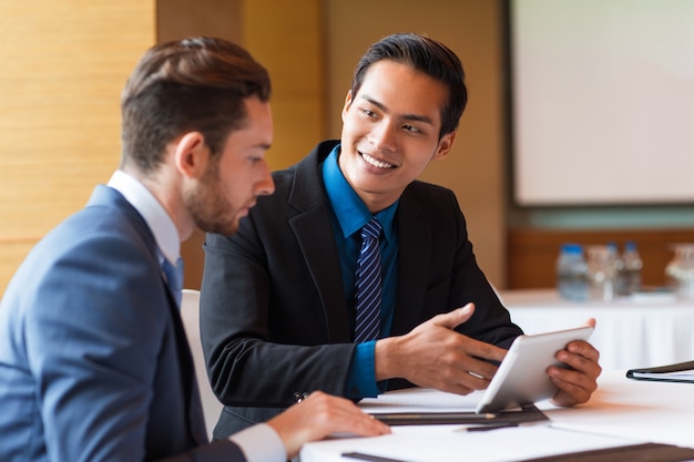 Primer plano de dos compañeros de trabajo sonrientes utilizando tableta