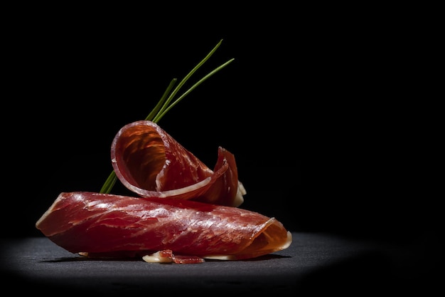 Foto gratuita primer plano de dos deliciosas lonchas de jamón una encima de la otra en un espacio oscuro