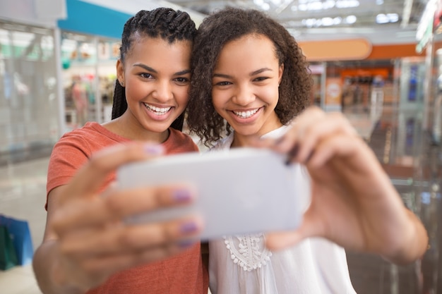Primer plano de dos muchachas negras que toman Selfie en alameda