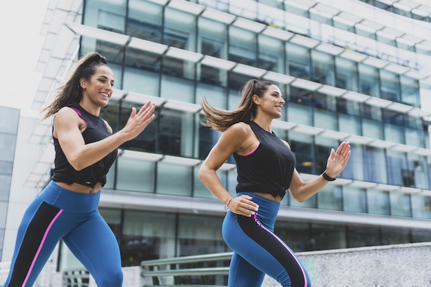 Primer plano de dos mujeres atractivas corriendo y haciendo ejercicios - concepto de fitness y deporte