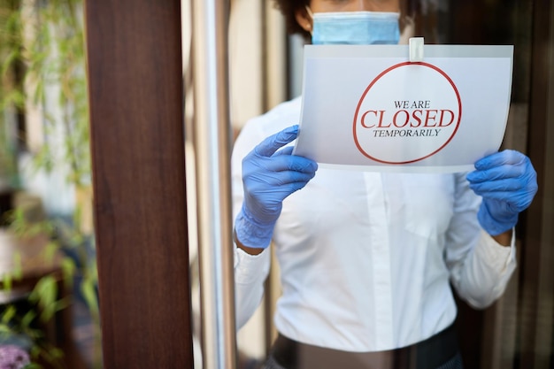 Primer plano del dueño del café colgando el cartel de cerrado debido a la pandemia de COVID19