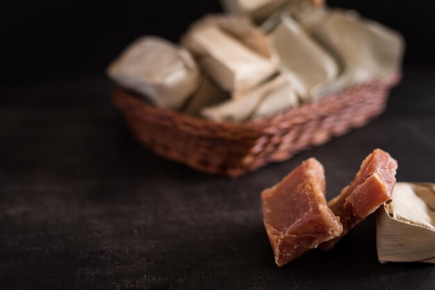 Primer plano de dulces colombianos cubiertos con hojas en una pequeña canasta en una mesa de madera