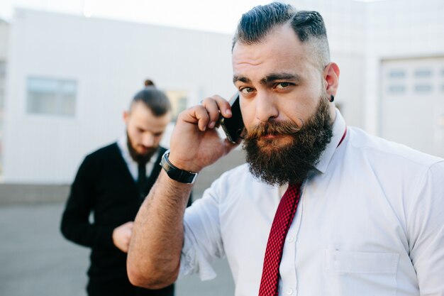 Primer plano de ejecutivo con barba hablando por teléfono