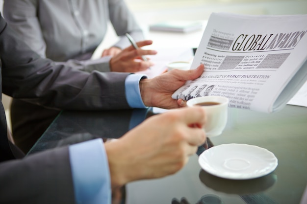 Primer plano de ejecutivo con un café y un periódico