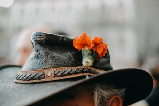 Foto gratuita primer plano de un elegante sombrero de vaquero con una flor de naranja en él usado por una persona mayor