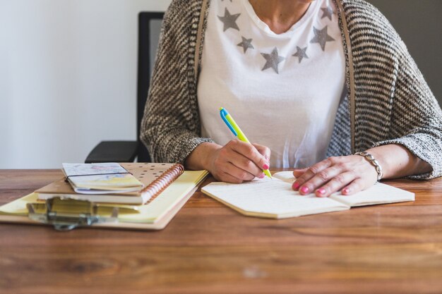 Primer plano de empleada escribiendo en una libreta