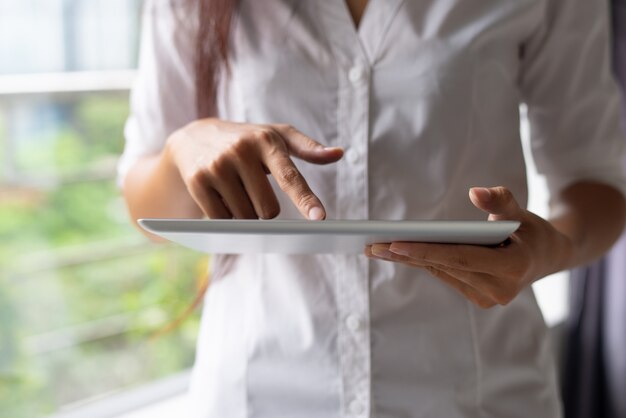 Primer plano de empresaria en camisa blanca utilizando dispositivo moderno