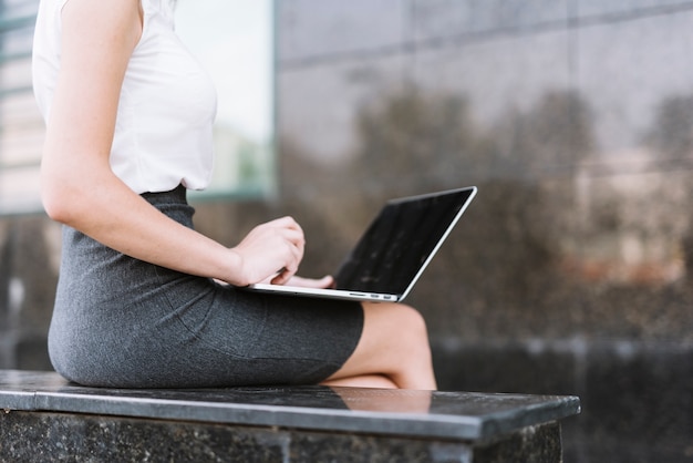 Primer plano de empresaria escribiendo en portátil sentado al aire libre