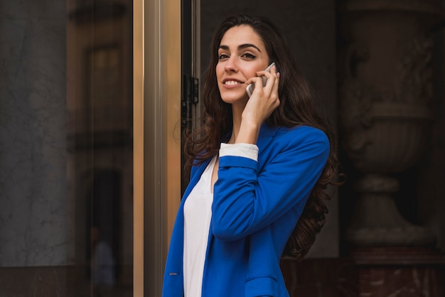 Primer plano de empresaria joven con teléfono móvil y chaqueta azul