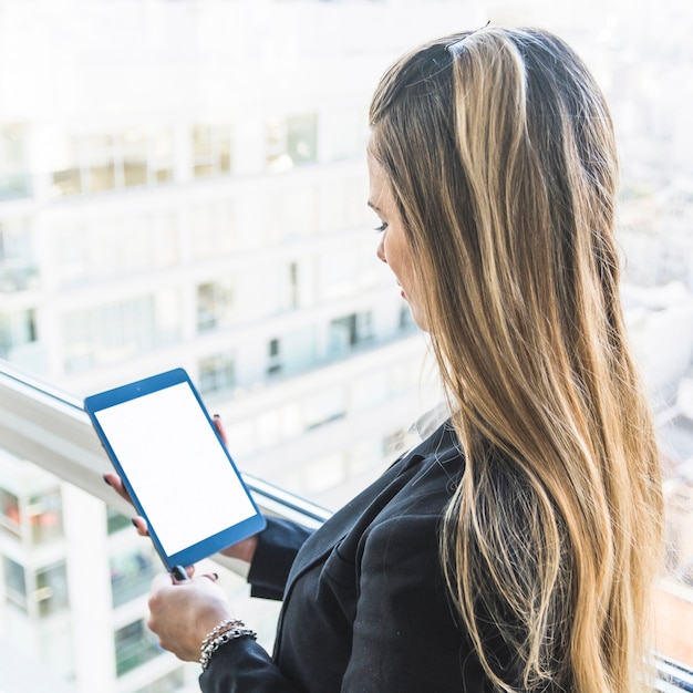 Primer plano de una empresaria mirando tableta digital con pantalla de visualización en blanco