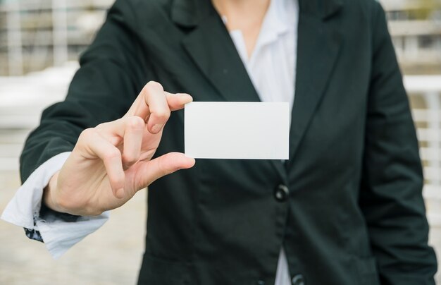 Primer plano de una empresaria mostrando tarjeta de visita en blanco blanco