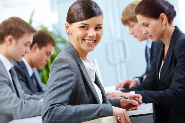 Primer plano de empresaria sonriente sujetando un bolígrafo