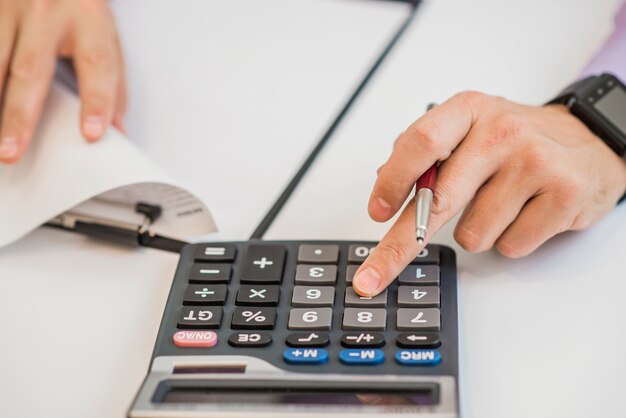 Primer plano del empresario calculando facturas utilizando calculadora