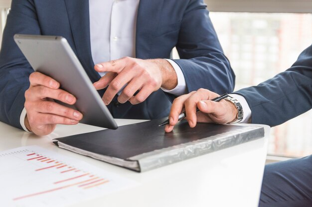 Primer plano de empresario discutiendo informe financiero sobre tableta digital