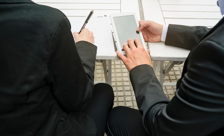 Foto gratuito primer plano del empresario y empresaria sosteniendo teléfono inteligente y escribiendo en papel al aire libre
