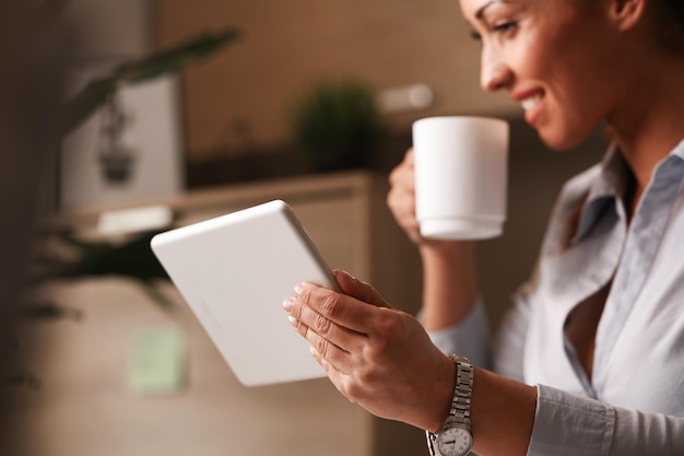 Primer plano de un empresario feliz disfrutando de un descanso para tomar café mientras navega por Internet en el panel táctil