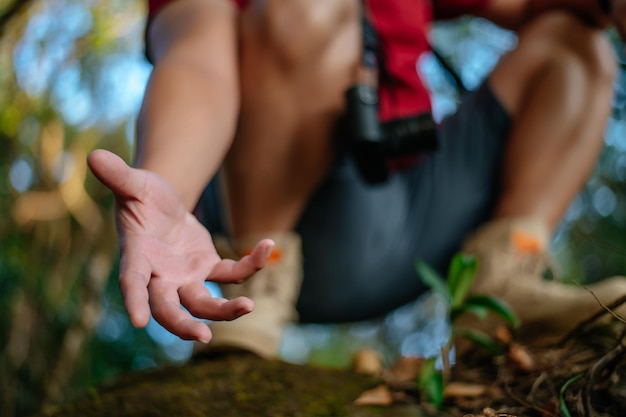 Primer plano y enfoque selectivo Joven excursionista en la parte superior sostenga a alguien que le ayude a escalar durante el viaje de trekking