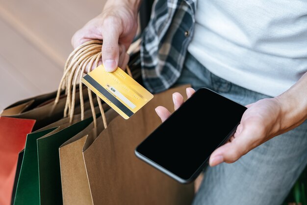 Primer plano y enfoque selectivo, mano de hombre sosteniendo múltiples bolsas de compras