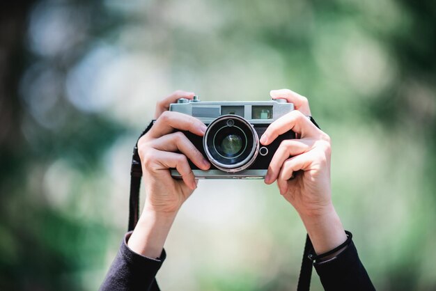 Primer plano y enfoque selectivo Manos de fotógrafa profesional sosteniendo una cámara digital para tomar instantáneas en el espacio de copia del bosque natural