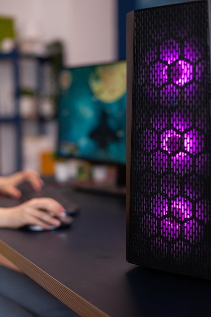 Primer plano del escritorio del sistema de luces LED RGB, mujer gamer jugando videojuegos de shooter espacial durante el campeonato en línea. Estudio de juegos equipado con configuración de transmisión profesional
