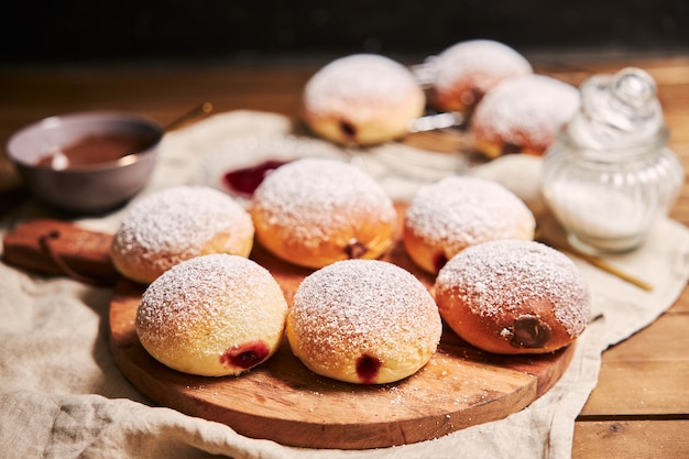 Primer plano de esponjosas rosquillas llenas de mermelada en una bandeja sobre la mesa bajo las luces