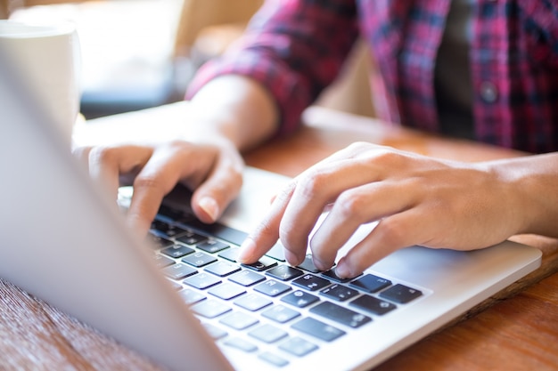 Primer plano de estudiante femenina escribiendo en la computadora portátil en la mesa