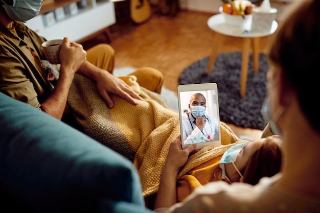 Primer plano de una familia que tiene una videollamada con su médico desde casa durante la pandemia del coronavirus