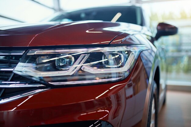 Primer plano del faro del coche rojo caro en la sala de exposición