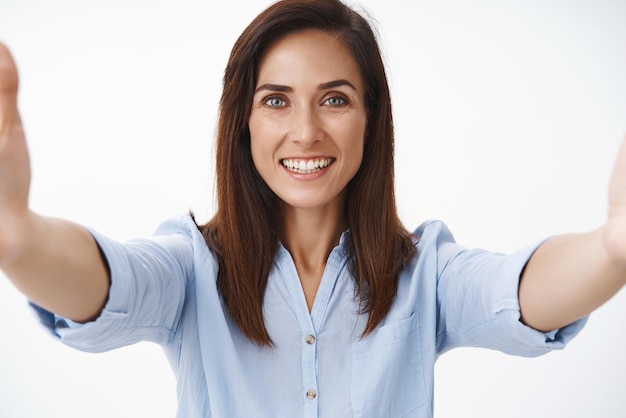 Foto gratuita primer plano feliz ambicioso alegre morena adulta caucásica mujer a partir de su propia madre blog compartir pensamientos cámara extender los brazos sonriendo ampliamente estado de ánimo optimista tomando selfie smartphone