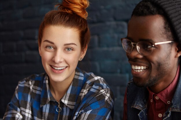 Primer plano de feliz linda pareja joven interracial divirtiéndose en el café durante el desayuno