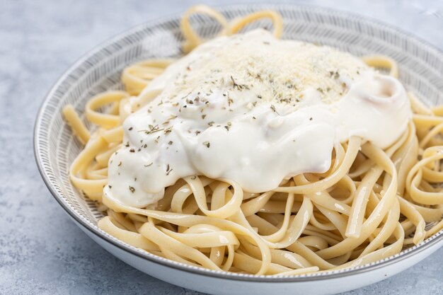 Primer plano de fettuccine cocido con crema y especias en un recipiente bajo las luces