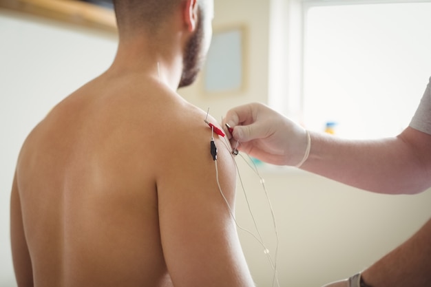 Foto gratuita primer plano de fisioterapeuta insertando agujas en el paciente