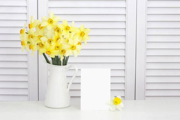 Primer plano de flor de narciso amarillo en el jarrón sobre persianas blancas