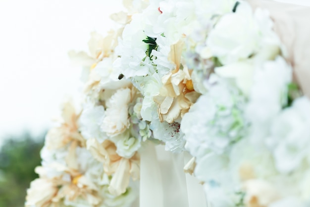 Un primer plano de flores blancas y beig en el altar de la boda