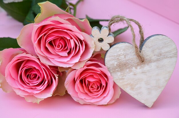 Primer plano de flores rosas rosadas con una etiqueta de madera de corazón con espacio para texto