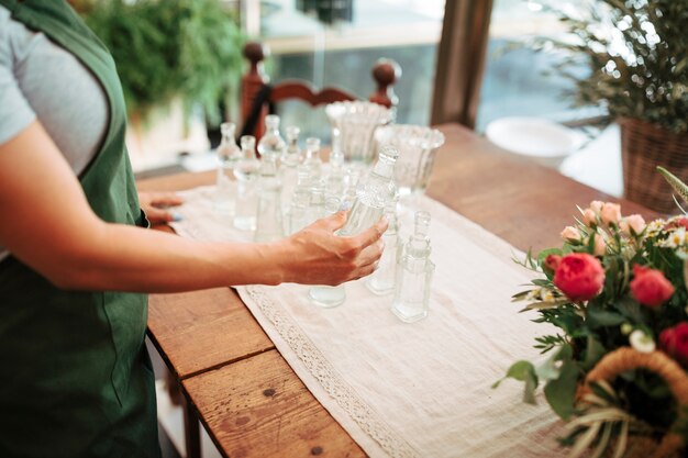 Primer plano, de, un, florista de sexo femenino, tenencia, botella de vidrio, en, floral, tienda