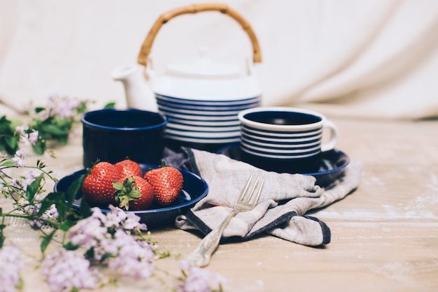 Foto gratuita primer plano de fresa y juego de té con flores rosadas sobre fondo de madera