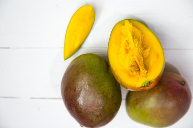 Primer plano de frutas de mango sobre fondo blanco de madera, concepto de fruta fresca tropical
