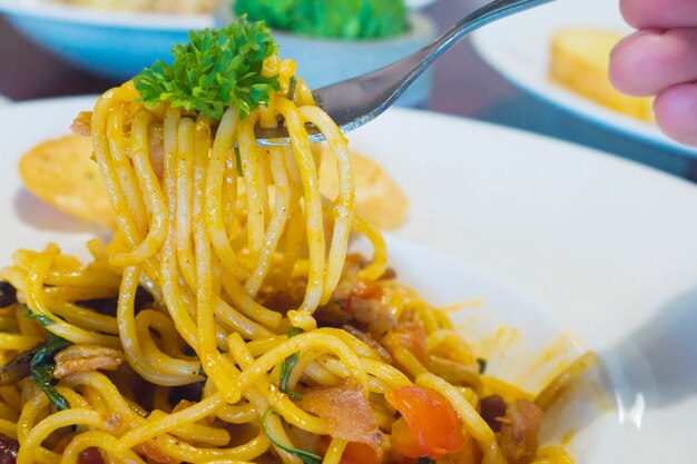 Primer plano de gente comiendo espaguetis con tocino