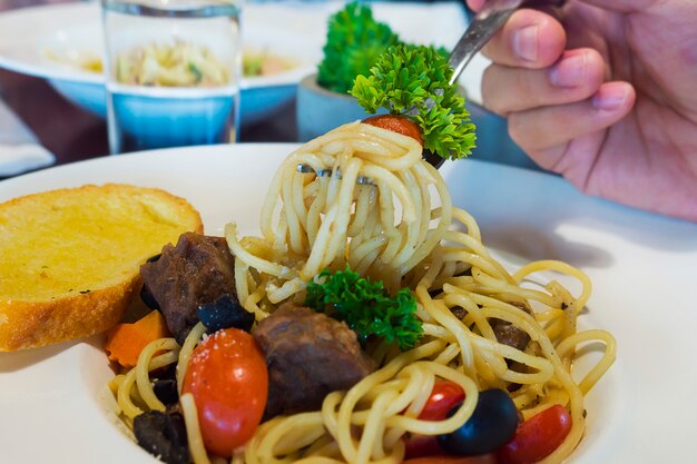 Primer plano de gente comiendo espaguetis con tocino