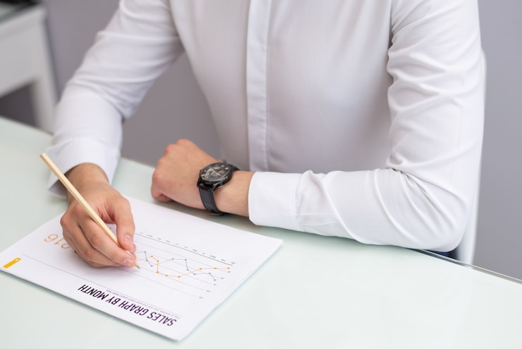 Foto gratuito primer plano del gerente sentado en la mesa y leyendo el informe de ventas