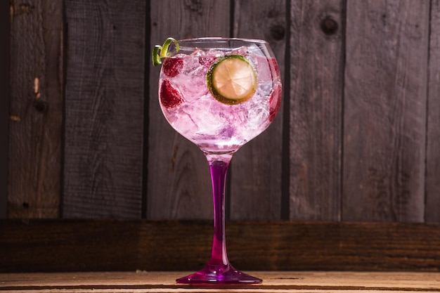 Foto gratuita primer plano de gin tonic con hielo y frambuesas sobre un fondo de madera