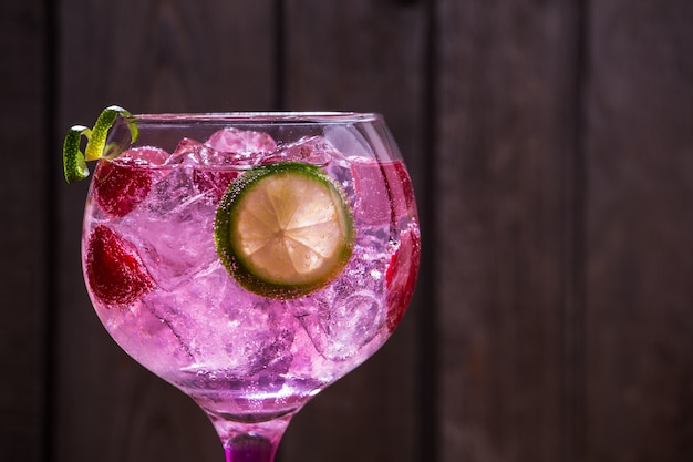 Primer plano de gin tonic rose con frambuesas y lima